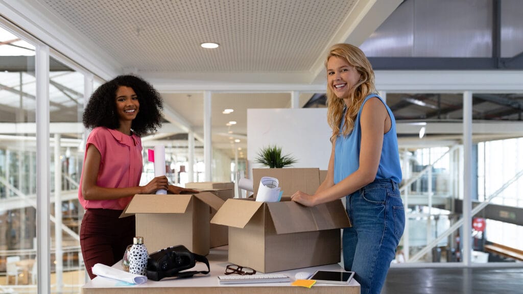 Two young employees packing office space