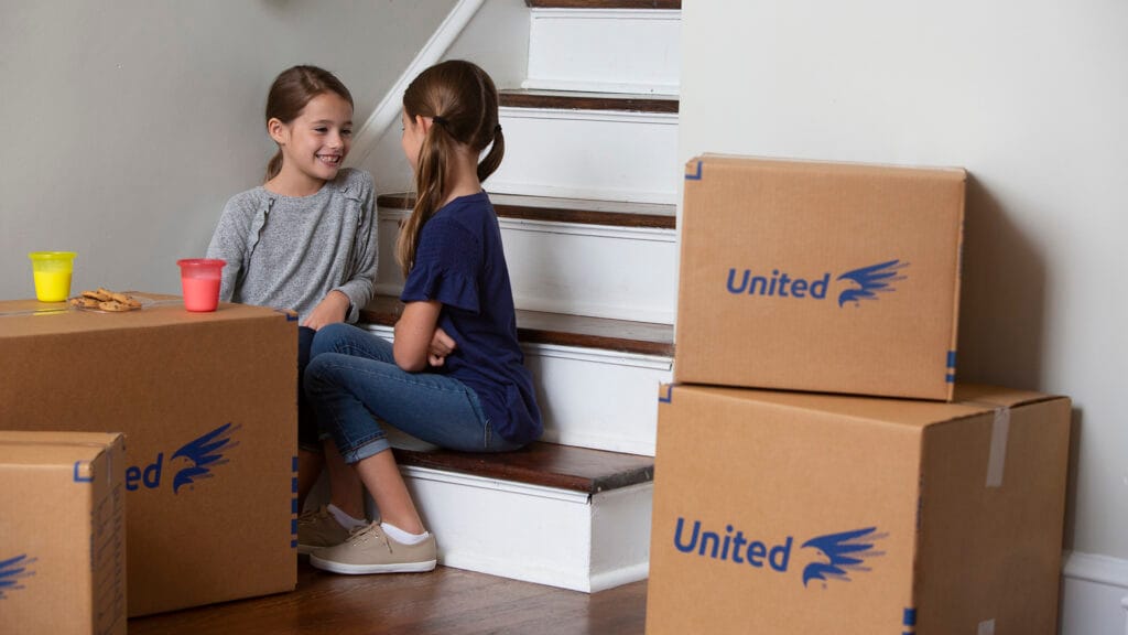 Young children eating cookies on top of moving boxes