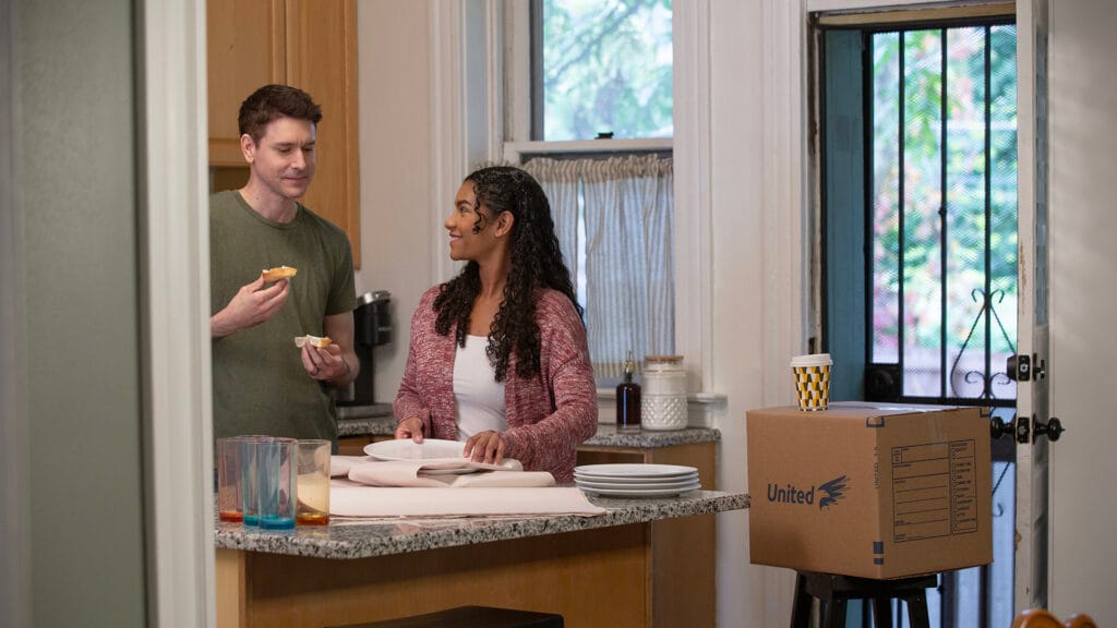 Young couple eating a bagel while packing up ceramic plates