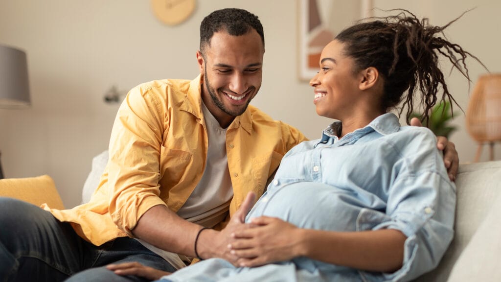 Happy couple expecting a baby, on the couch