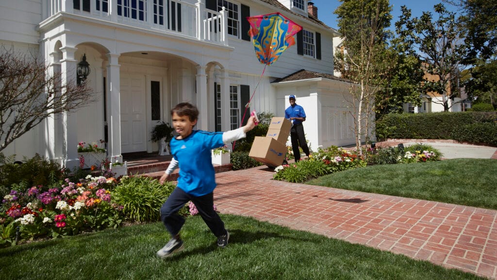 Child playing outdoors with a kite, and Christofferson employee in the background