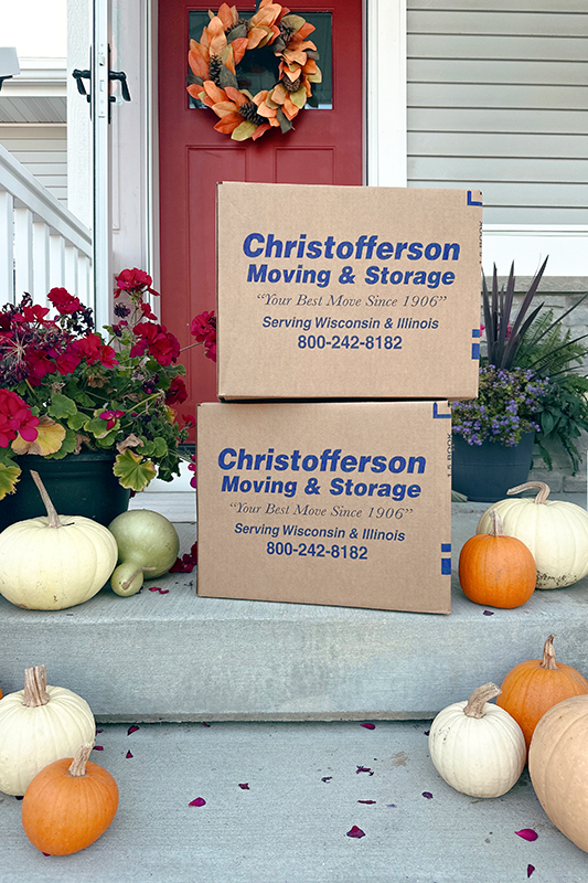 Two Christofferson Moving & Storage boxes in front of a residential home with pumpkins surrounding them